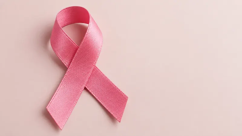Eine rosa Schleife liegt auf einer neutralen Fläche.