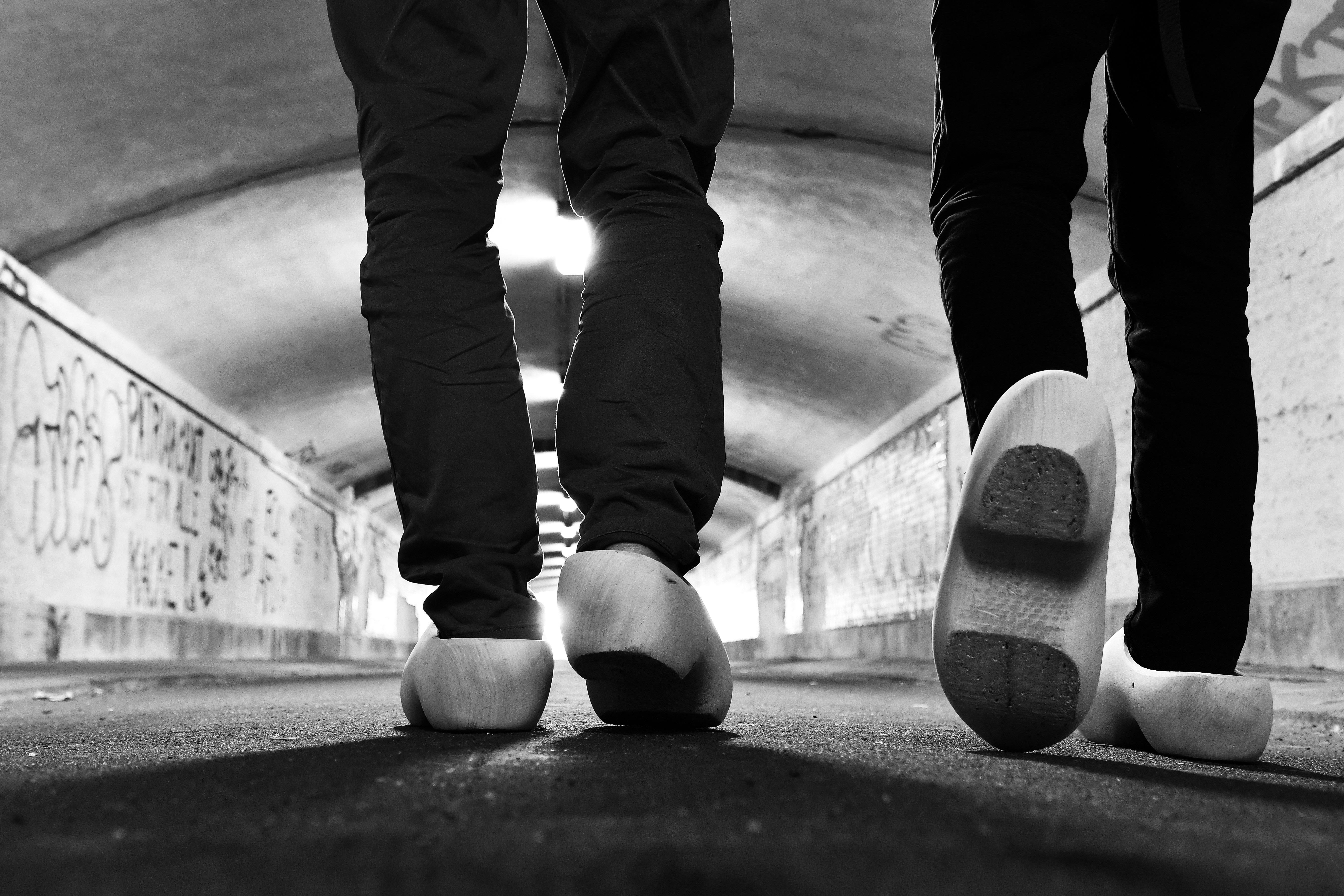 Zwei Personen gehen in Holzschuhen durch den Zittauer Bahnhofstunnel.