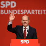 Olaf Scholz auf der Bühne des SPD-Bundesparteitags in Berlin. Der Altkanzler steht vor einem roten Hintergrund mit SPD-Logo und hält eine Abschiedsrede an die Delegierten.