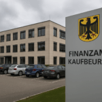 Ein modernes Verwaltungsgebäude des Finanzamtes Kaufbeuren, davor mehrere geparkte Autos. Der Himmel ist bewölkt. Das Bild symbolisiert den Ort der Rekordsteuerzahlung der Unternehmerfamilie Thiele.
