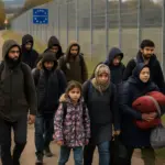 Gruppe Migranten an Grenzzaun zwischen Polen und Deutschland