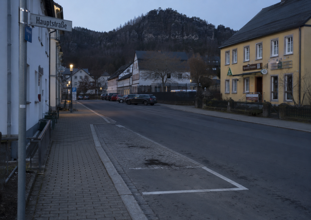 Symbolbild zur Hauptstraße in Oybin nach einem Autodiebstahl mit leerer Parkfläche in der Abenddämmerung