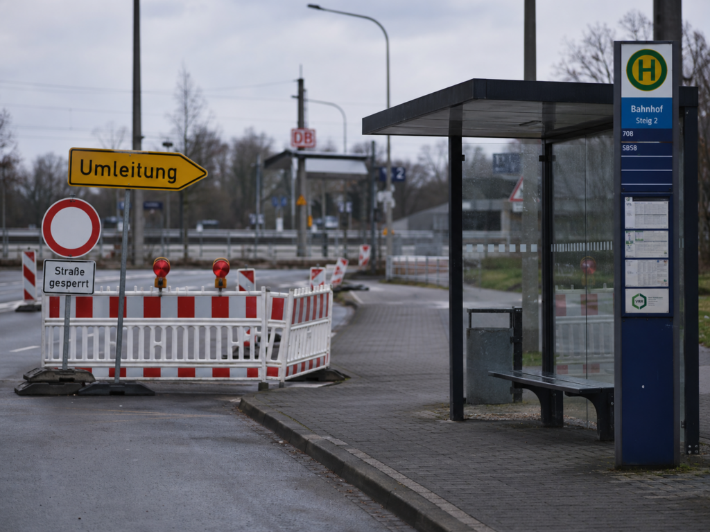 Symbolbild zur Sperrung der Bahnhofstraße in Zittau mit deutscher Bushaltestelle, Umleitungsschild und Baustellenabsperrung